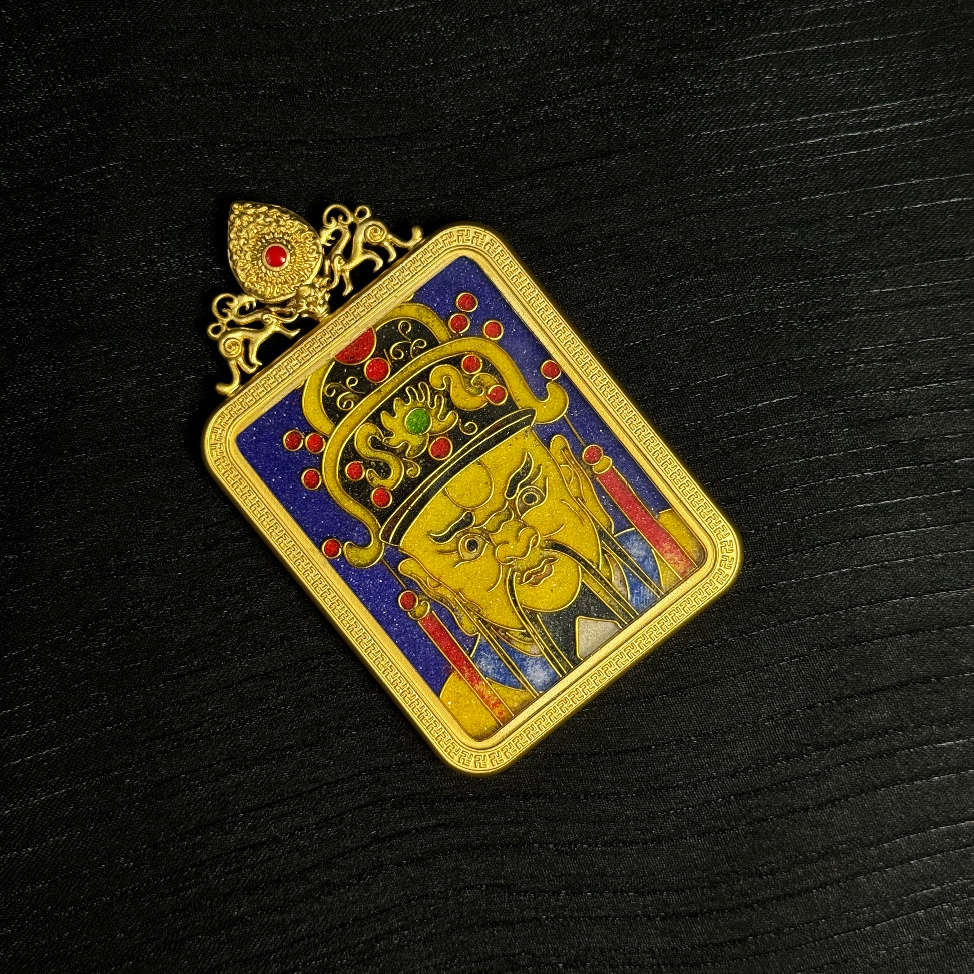Top angle view of Dragon King Wuye cloisonné enamel mini thangka pendant featuring a gold-plated copper frame, detailed golden deity portrait, ornate crown with red enamel accents, and deep blue cloisonné enamel background.