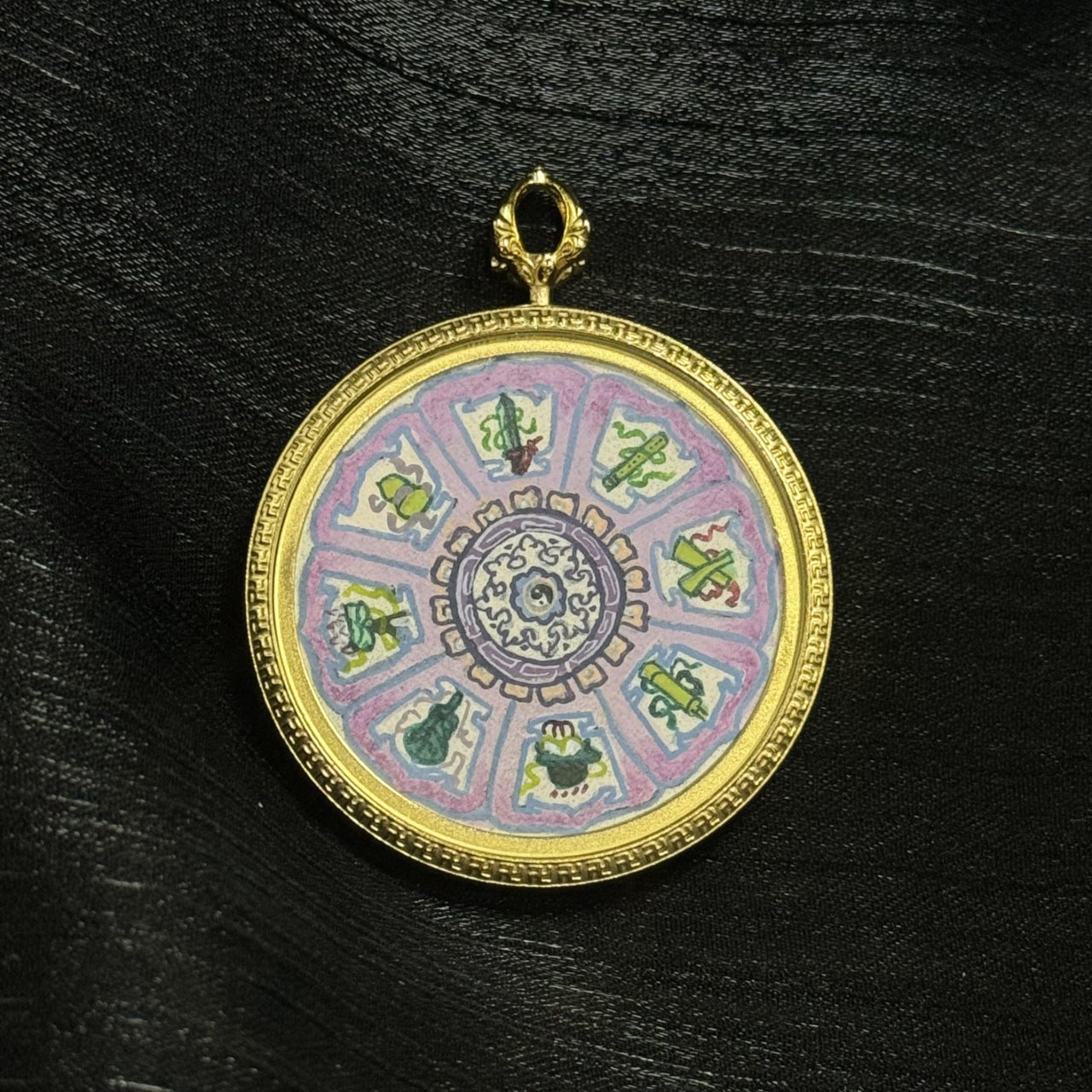 Full-frame view of the Eight Immortals Bagua mini thangka pendant on a black textured background, showing the complete circular composition, gold-tone frame, and top loop.