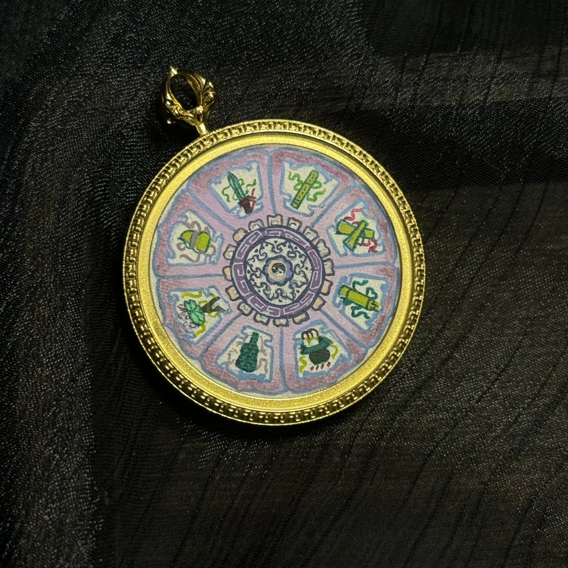 Mini thangka jewelry pendant displaying a mandala composition of the Eight Immortals sacred symbols, painted with soft mineral pigment colors and surrounded by a decorative gold frame.