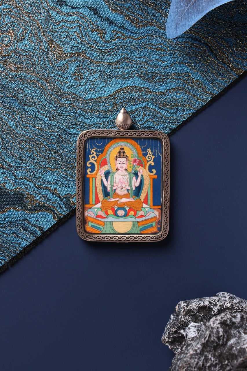 Front view of Four-Armed Avalokiteshvara (Chenrezig) mini thangka pendant with detailed silver frame and blue thangka background