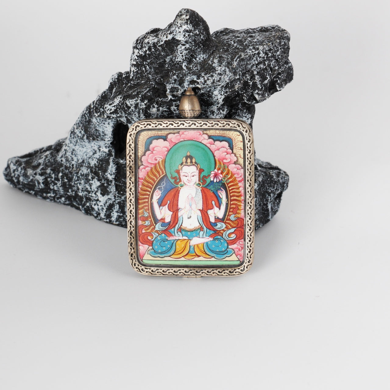 Front view of a Four-Armed Avalokiteshvara mini Thangka pendant, fully hand-painted with mineral pigments and framed in a pure silver gawu-style pendant case with traditional Tibetan decorative patterns.