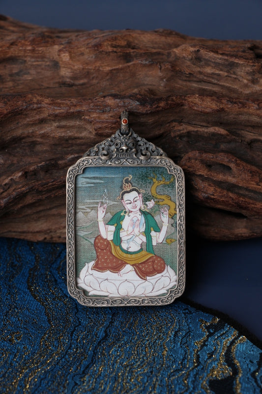 Close-up detail of Four-Armed Avalokiteshvara mini thangka pendant, showing traditional Tibetan hand-painted mineral pigment artwork inside a vintage silver case