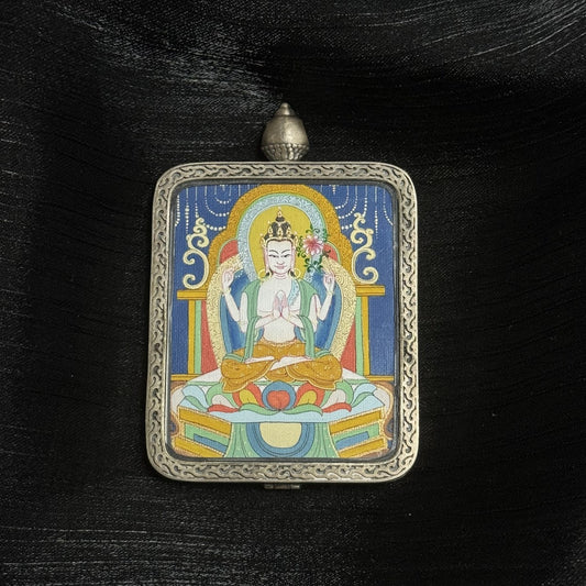 Hand-painted Four-Armed Avalokiteshvara (Chenrezig) mini thangka pendant showing the bodhisattva of compassion seated on a lotus throne inside an engraved Dunhuang Nine-Color Deer silver gawu frame