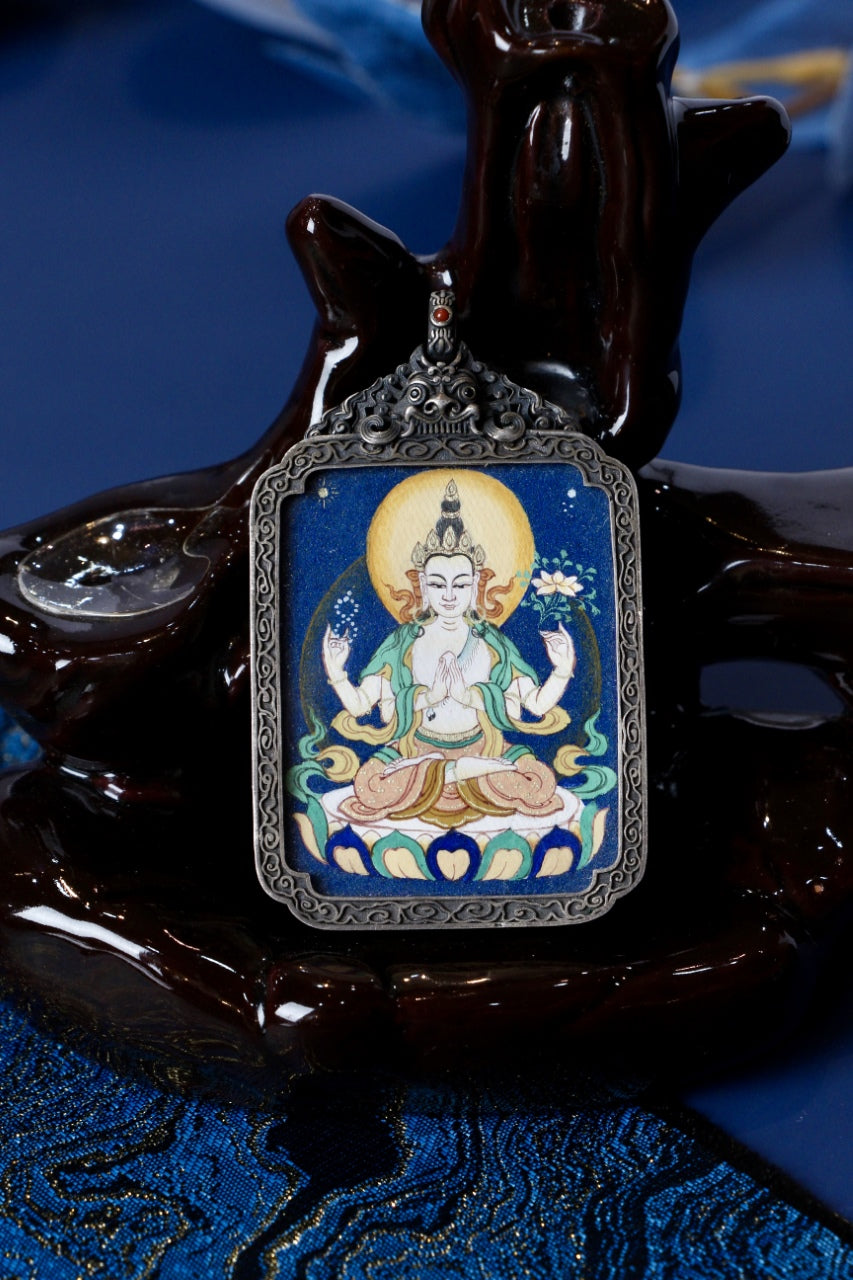 Four-Armed Avalokiteshvara (Chenrezig) mini thangka pendant from Tibet, hand-painted with mineral pigments, set in a vintage silver case—symbol of compassion, family protection, and health.