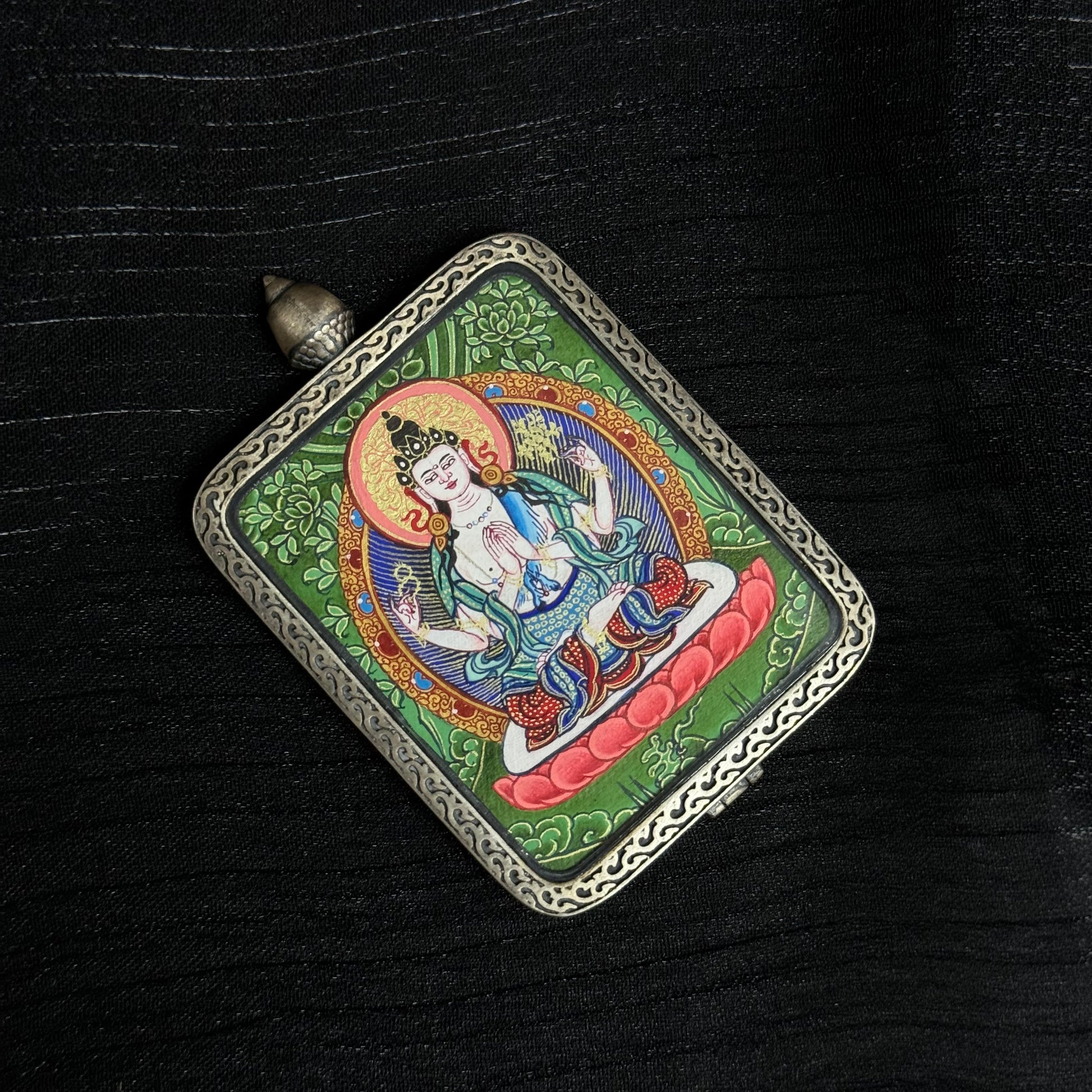 Top angle view of Four-Armed Avalokiteshvara mini thangka pendant highlighting hand-painted Tibetan thangka artwork and detailed metal pendant frame