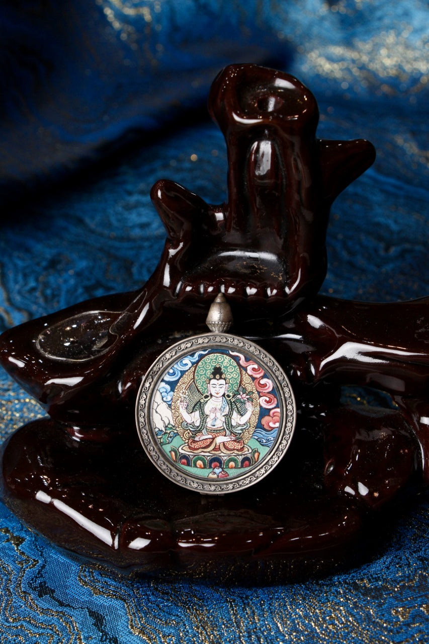 Four-Armed Avalokiteshvara (Chaturbhuja Lokeshvara) double-sided thangka pendant displayed on a wooden stand, fully hand-painted in traditional Rebgong style with auspicious cloud background and 925 silver frame