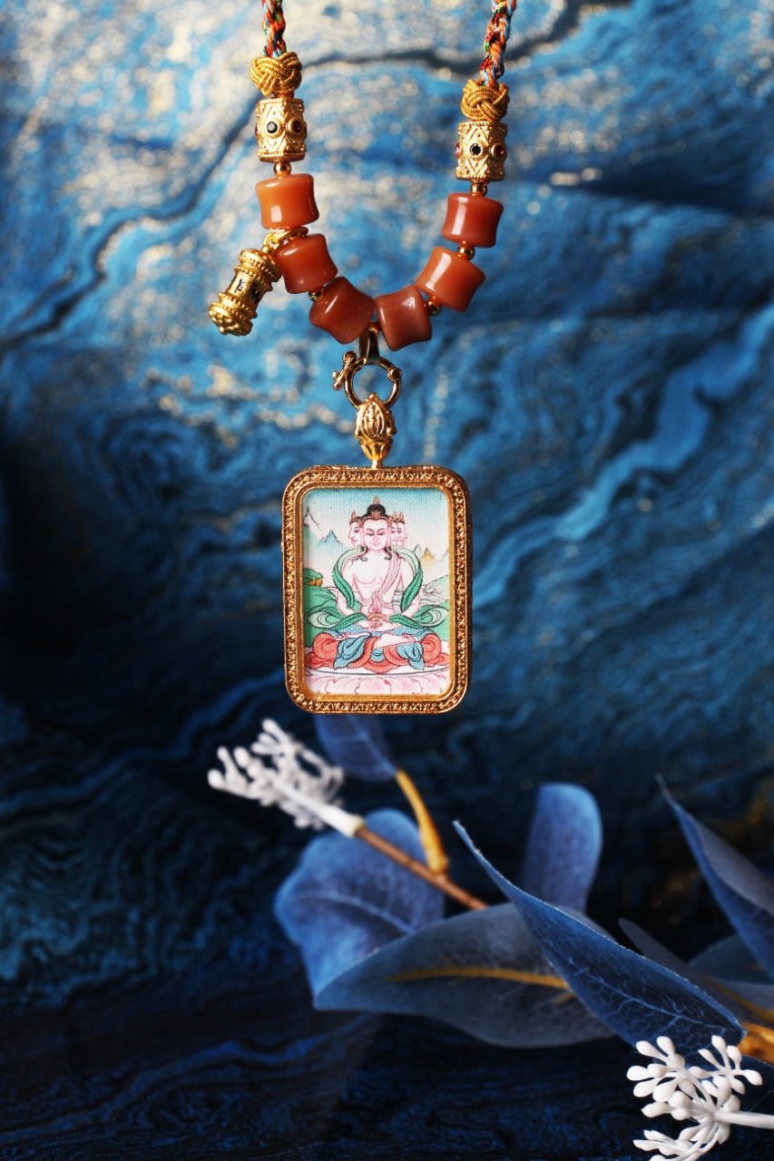Front view of Vairocana Buddha mini thangka pendant focusing on the pendant connector ring, braided cord knots, orange beads, and the rectangular framed hand-painted artwork