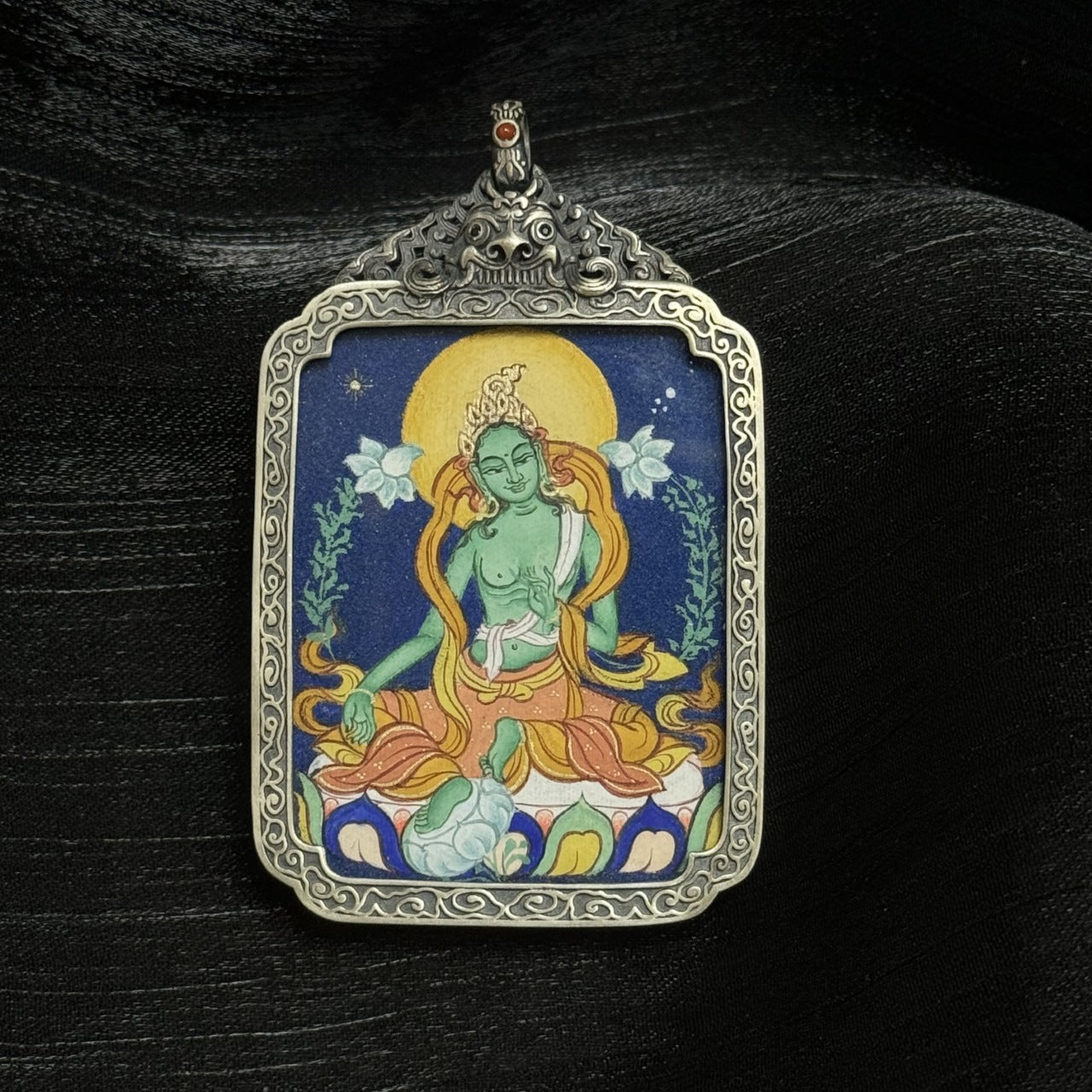 Front view of a Green Tara mini thangka pendant set in an ornate vintage-style silver case, hand-painted with durable mineral pigments.