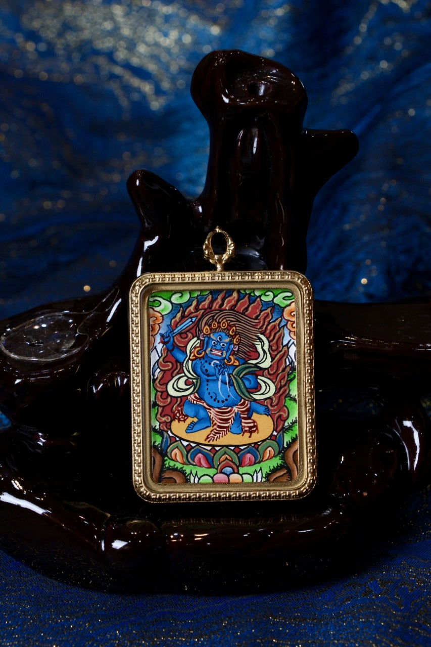 Close-up of a Nepalese hand-painted thangka pendant showing Acalanatha surrounded by flames, representing steadfast resolve, wisdom, and the suppression of negative forces.