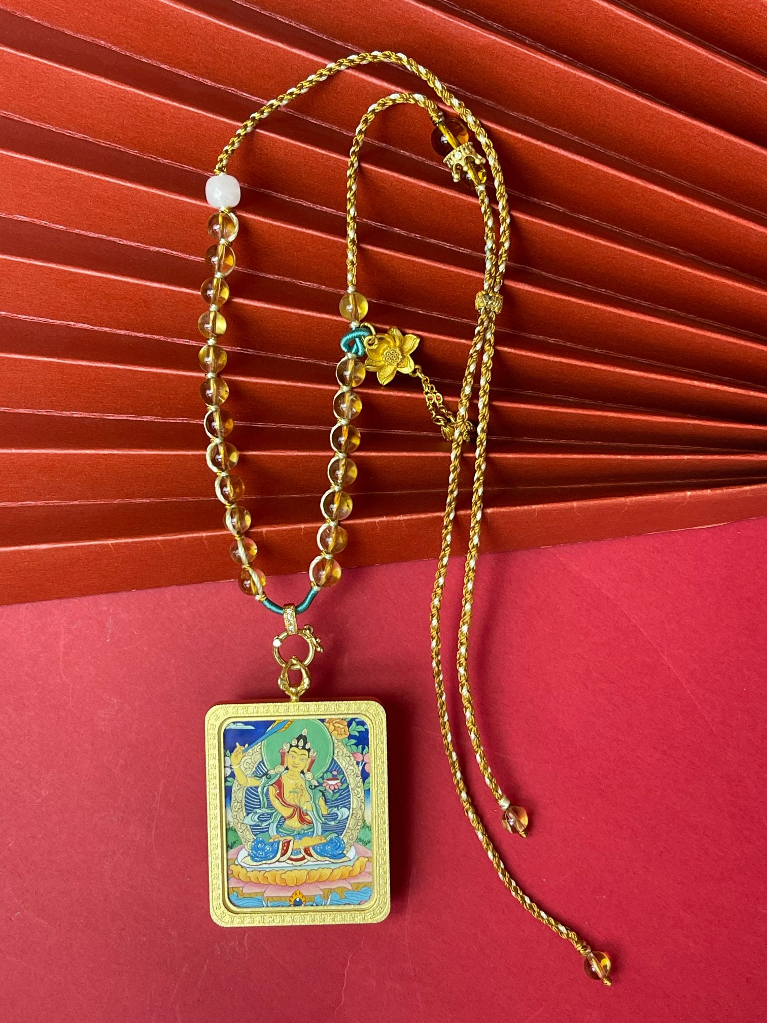 Full necklace view of Manjushri Bodhisattva mini thangka pendant showing hand-painted Tibetan mineral pigment artwork, copper frame, and yellow crystal handwoven cord