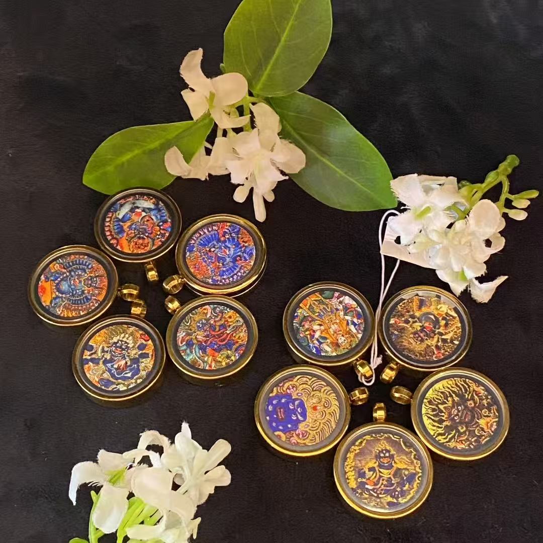 Assorted gold-accented Tibetan thangka pendants for wholesale buyers, mixed deity designs in gau box format