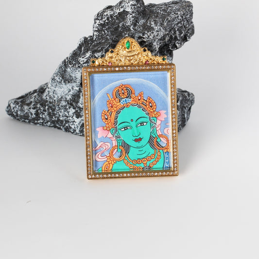 Front view of Green Tara Buddha head mini thangka pendant, hand-painted with mineral pigments, set in a gold-tone titanium steel case with crystal-style border and ornate top detail
