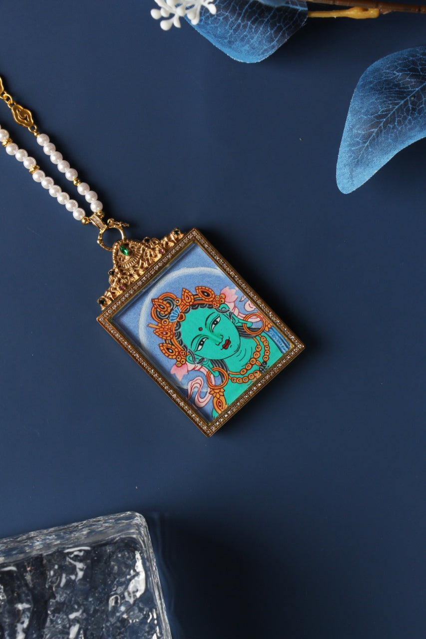 Angled view of Green Tara head thangka pendant, Nepal handmade Buddhist artwork using natural mineral pigments, framed in jewelry-grade titanium steel