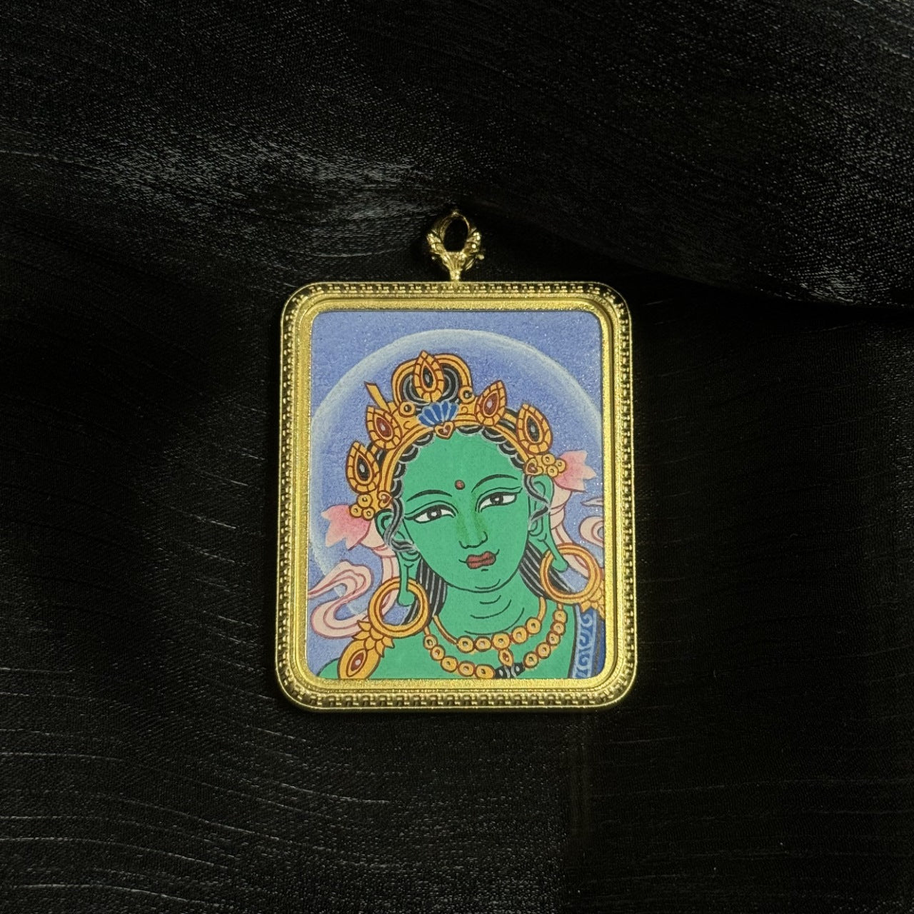 Front view of Green Tara head miniature thangka pendant with serene expression, traditional Buddhist crown, halo background, and fine mineral pigment colors.
