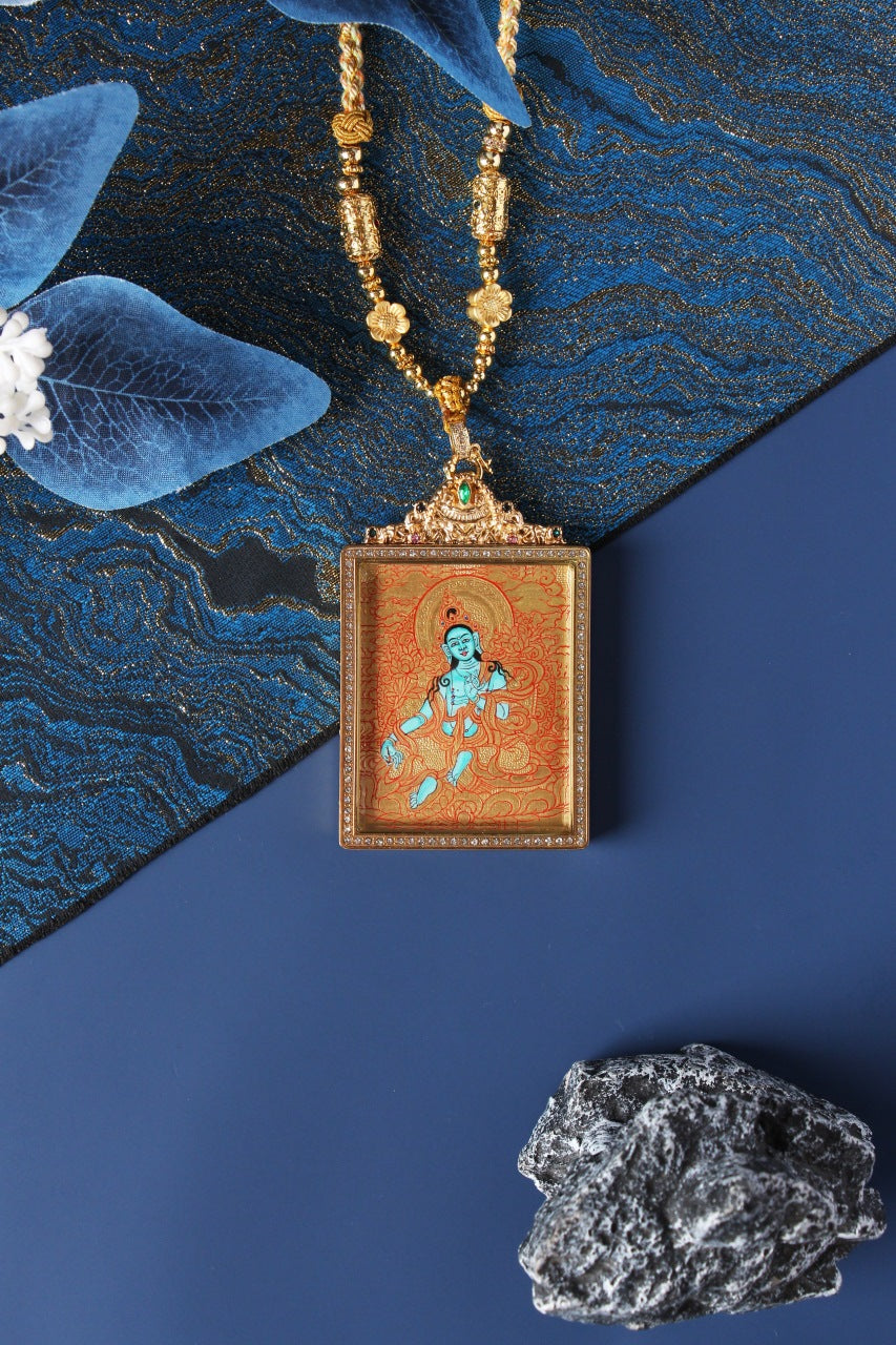 Hand-painted Green Tara mini thangka pendant on gold-ground background, square jewelry-style frame with crystal border, ornate top setting with green stone, beaded necklace display