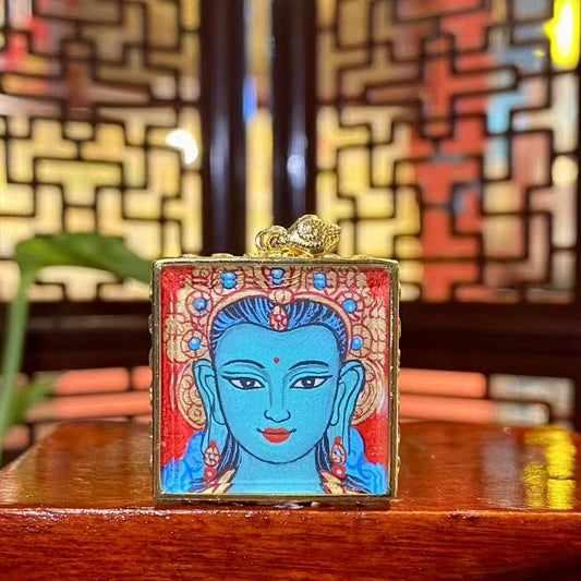 Front view of a hand-painted Green Tara mini thangka pendant housed in a traditional copper Ghau box