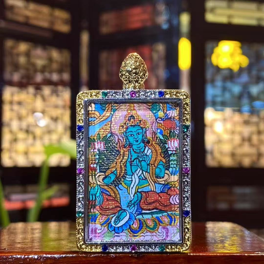 Front view of a hand-painted Green Tara mini thangka pendant in a traditional copper Ghau box, size 25 × 35 mm