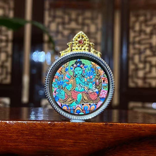 Front view of a hand-painted Green Tara thangka pendant with a complete seated image in an S925 silver Ghau box, 24 mm