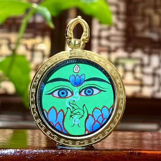 Front view of a hand-painted Green Tara thangka pendant in a round titanium steel Ghau box, 25 mm diameter