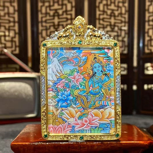 Front view of a hand-painted Green Tara thangka pendant in a gilded copper Ghau box, size 55 × 45 mm