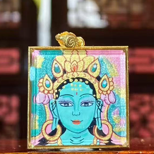 Front view of a double-sided hand-painted Green Tara thangka pendant in an 18K gold Ghau box with sapphire crystal glass