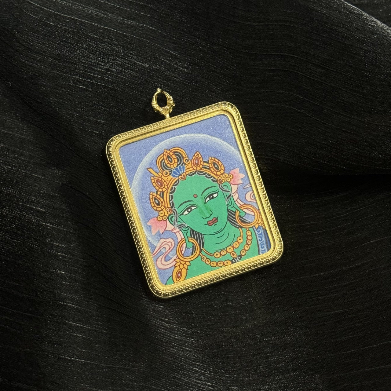 Close-up angled view of Green Tara head thangka pendant showing gold framed miniature thangka artwork, green Tara face, crown jewelry, and traditional Himalayan painting details.