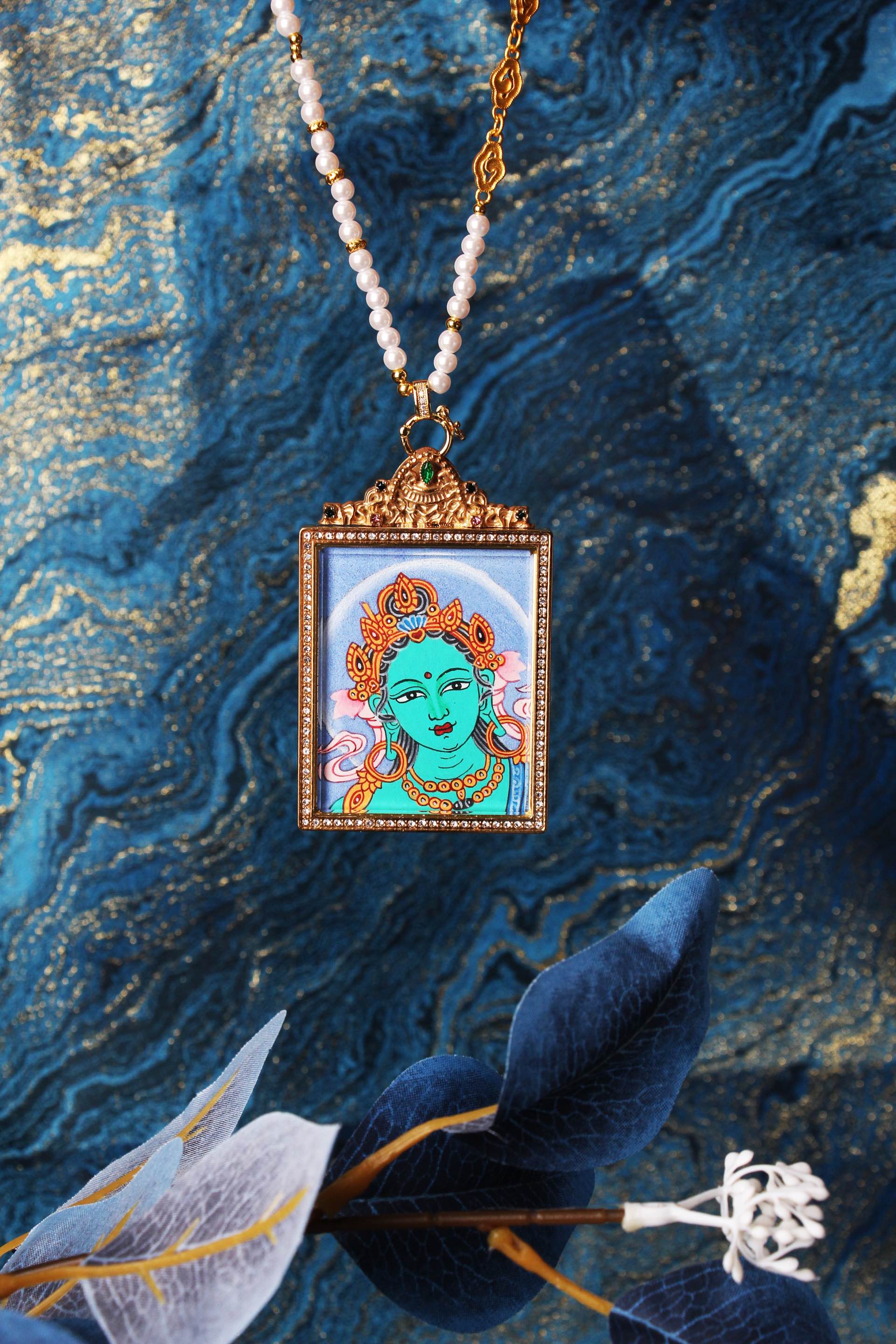 Green Tara head thangka necklace displayed on textured fabric background, Nepal raw mineral pigment painting, Buddhist protective deity pendant for blessing and longevity