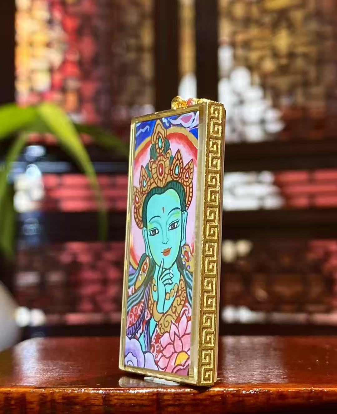 Side view of a double-sided Tibetan Thangka pendant set in an 18K gold Gau box with sapphire crystal, crafted in Rebgong style.
