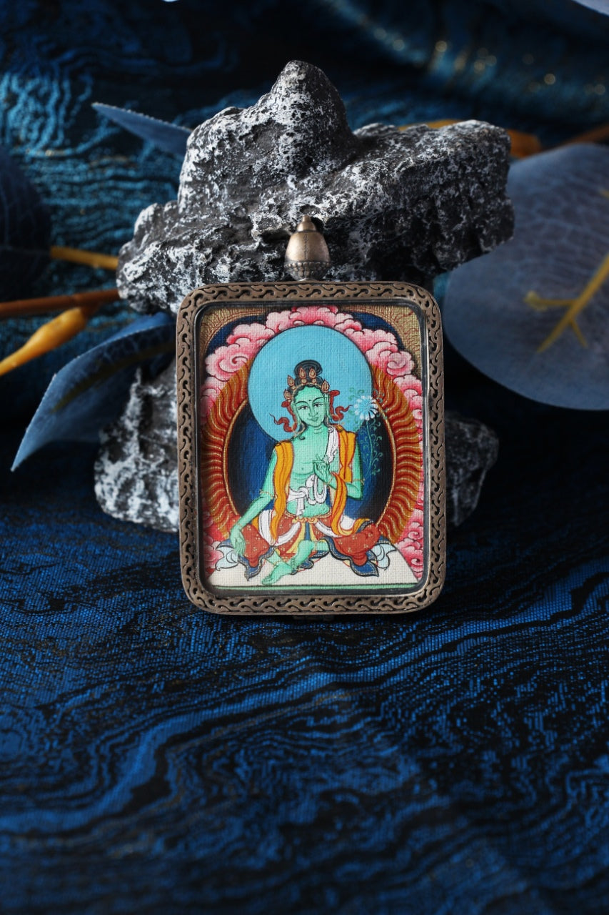 Close-up product photo of the Green Tara mini thangka pendant highlighting hand-painted mineral pigment craftsmanship and the sterling silver protective case, designed for collectors and practitioners seeking a durable portable thangka piece.