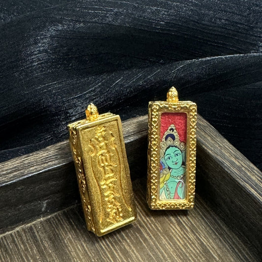 Front and back view of a Green Tara mini thangka pendant, showing the hand-painted green face with jeweled crown, red background panel, and gold-tone raised frame, alongside the back of the copper case with embossed script and textured surface.