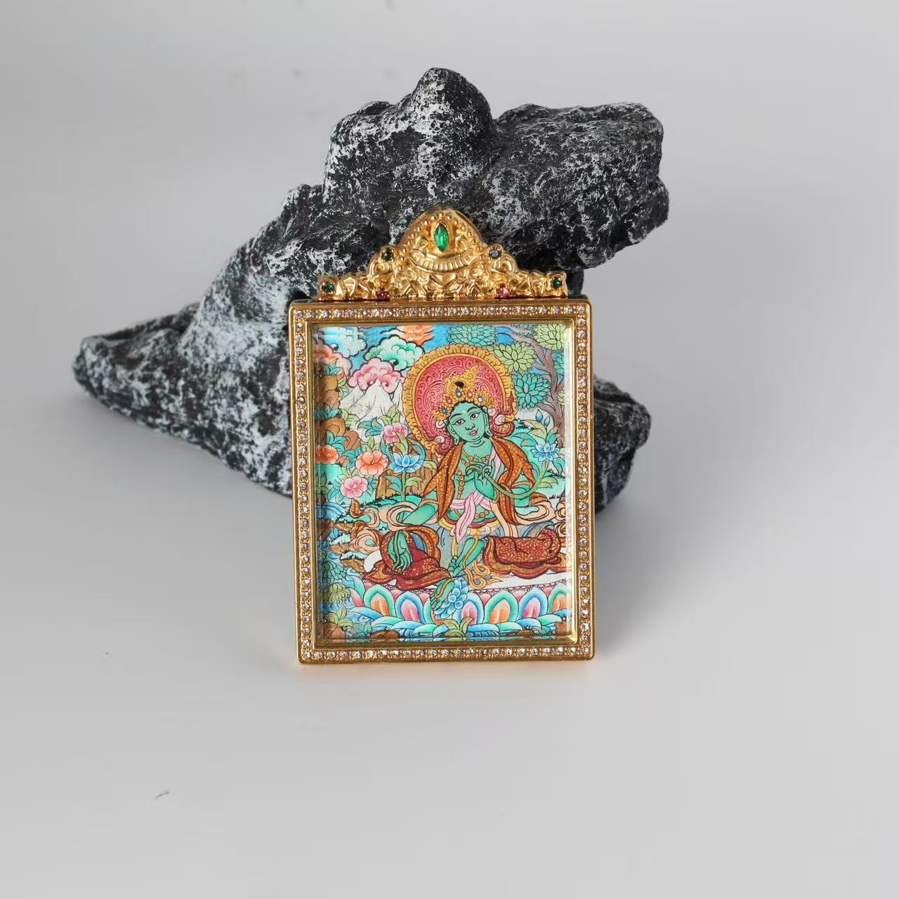 Front view of Green Tara mini thangka pendant, fully hand-painted with mineral pigments, vibrant layered colors, set in a gold-tone double-sided titanium steel case with decorative detailing