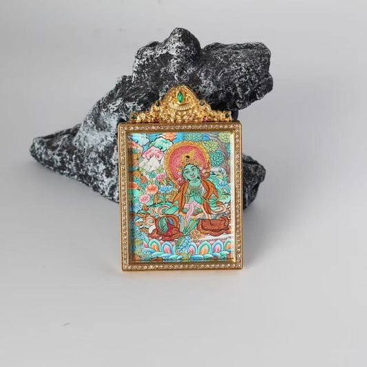 Front view of Green Tara mini thangka pendant, fully hand-painted with mineral pigments, vibrant layered colors, set in a gold-tone double-sided titanium steel case with decorative detailing