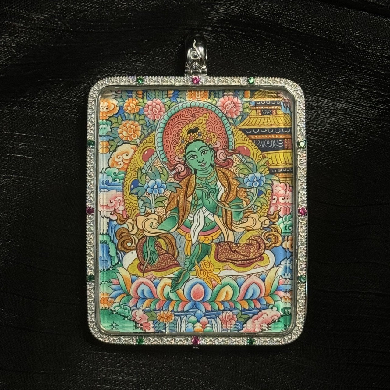 Detailed close-up of a Green Tara mini thangka pendant highlighting the lotus base, intricate halo, jewelry details, and mineral pigment painting.