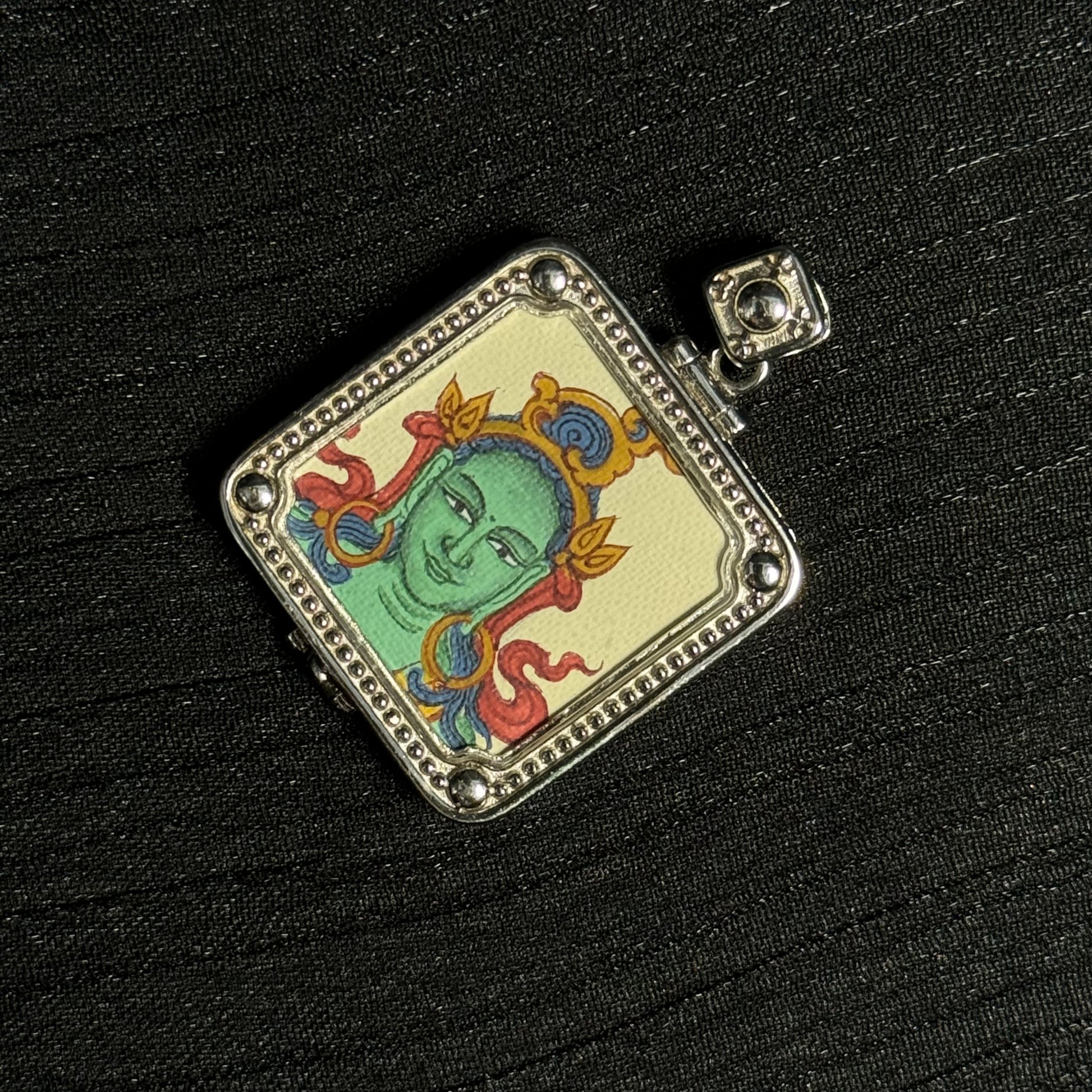 Close angled view of Green Tara miniature thangka pendant highlighting Tibetan painting details and mineral pigment texture