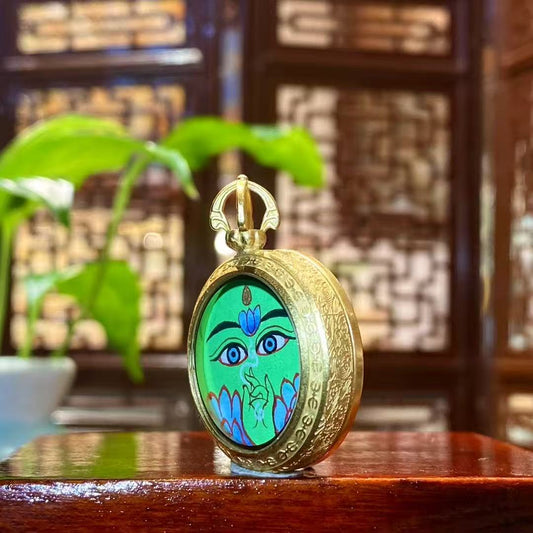 Side detail of a Green Tara mini thangka pendant showing the round titanium steel Ghau box and minimalist frame