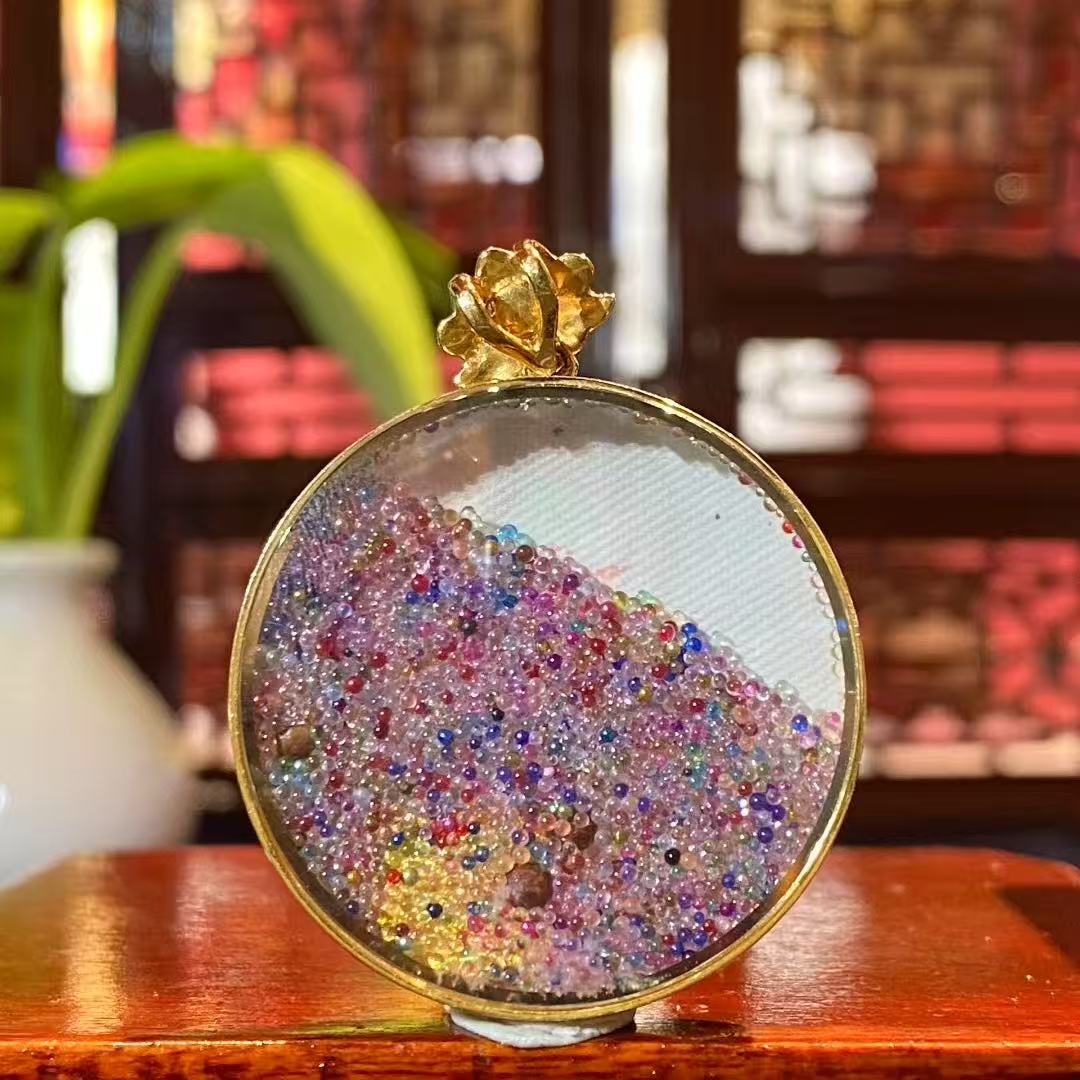 Back view of a round Green Tara Thangka pendant showing the solid metal back of the 18K gold Gau box with smooth finish and protective structure.
