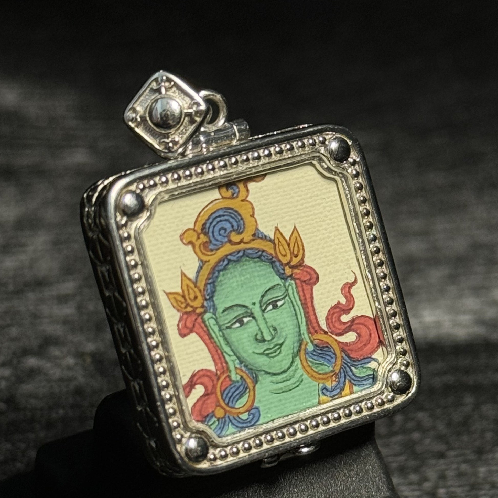 Angled view of Green Tara mini thangka pendant showing Tibetan Buddhist deity painting with detailed mineral pigment colors