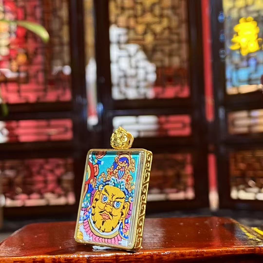 Side view of a double-sided Gau Thangka pendant showing the slim 18K gold frame and refined miniature craftsmanship
