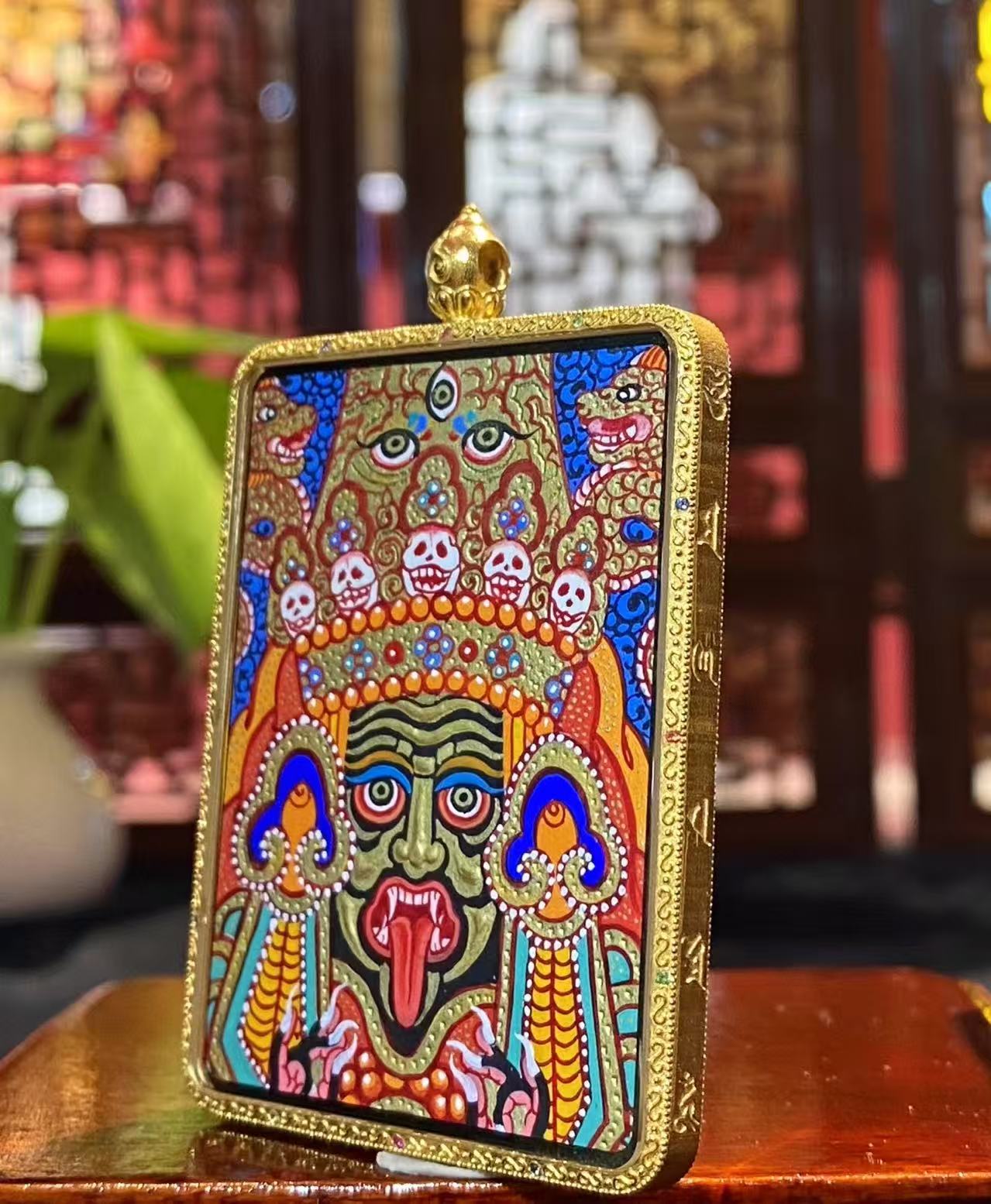Side view of a Tibetan Thangka pendant set in an 18K gold Gau box with sapphire crystal cover, showcasing full-detail Rebgong handcraftsmanship.
