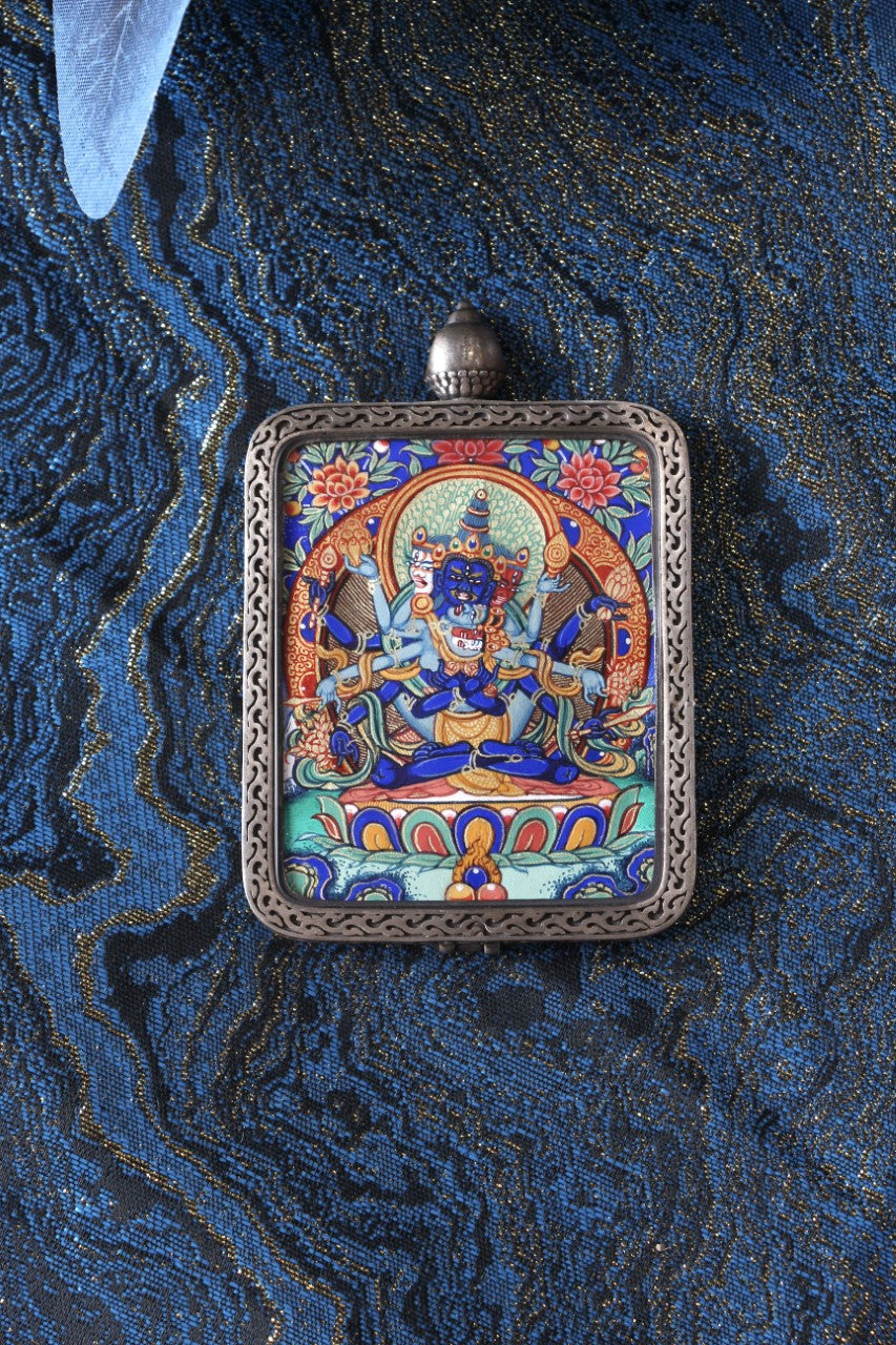 Flat lay of a Guhyasamāja Vajra mini thangka pendant showing the hand-painted iconography, floral border elements, and the pure silver pendant frame, suitable for Shopify product presentation and collectors’ display.