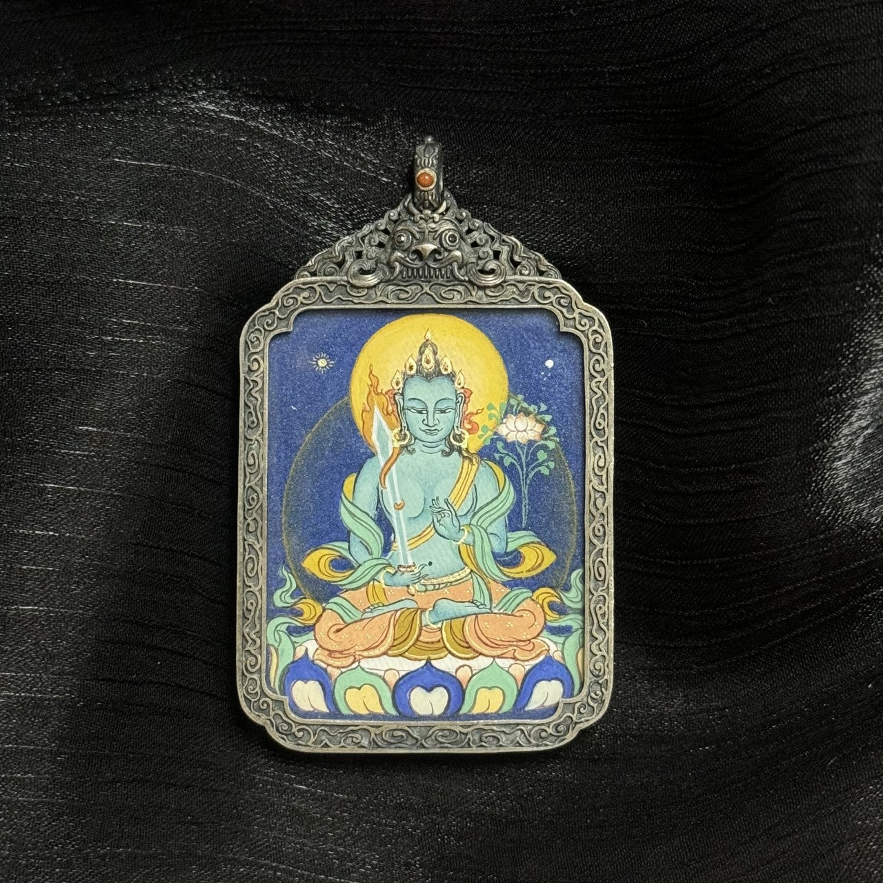 Close-up view of Akasagarbha Bodhisattva thangka pendant highlighting layered mineral pigment texture, flowing ribbons, lotus base, and antique silver frame craftsmanship.