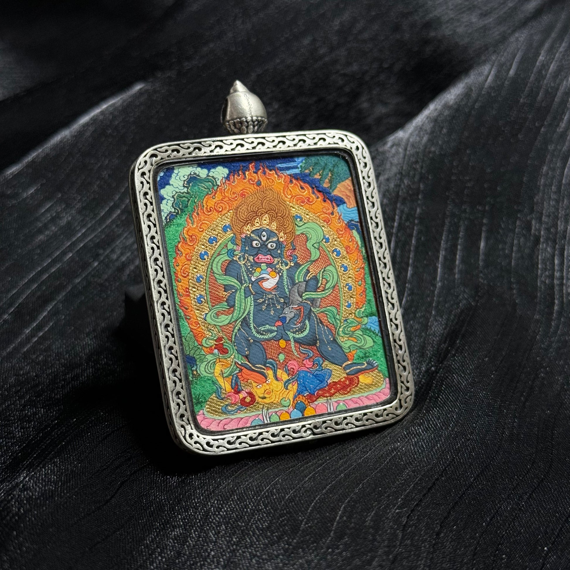 Close perspective of Black Jambhala mini thangka pendant highlighting gold powder detailing, intricate linework and traditional Tibetan thangka composition