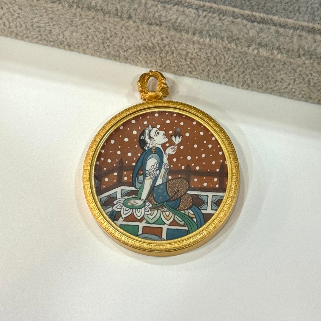 Front view of a hand-painted Holding Lotus Avalokiteshvara mini thangka pendant, painted with mineral pigments and set in a round matte copper case with decorative rim.