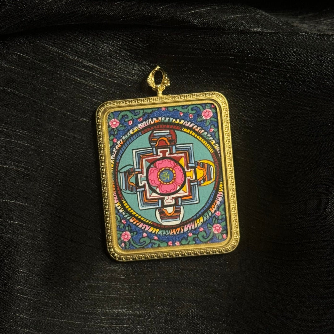 Front view of Buddhist mandala mini thangka pendant showing traditional mandala geometry painted with mineral pigments inside a metal pendant frame