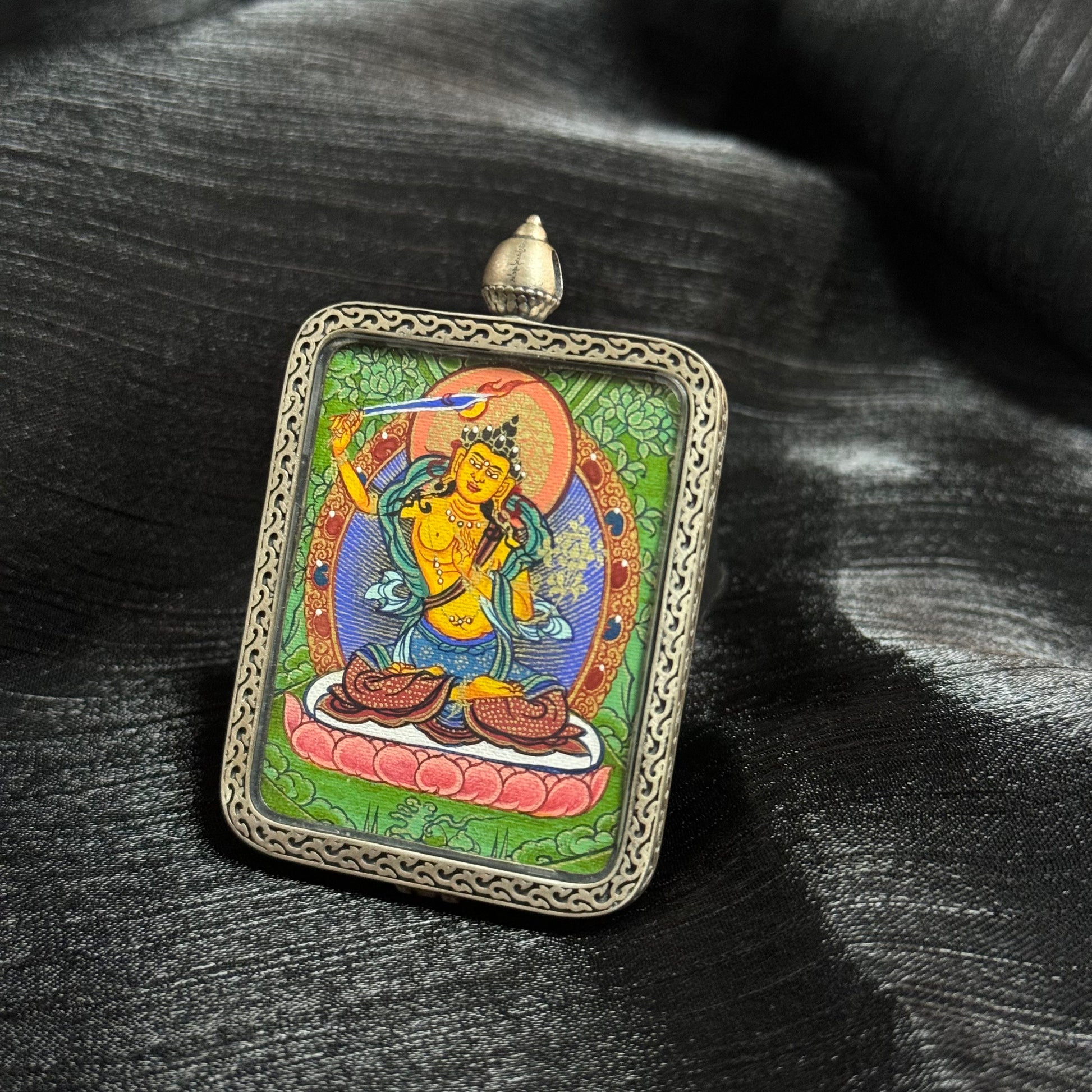 Detailed view of Manjushri Bodhisattva thangka pendant showing vibrant mineral pigment colors and traditional Tibetan iconography