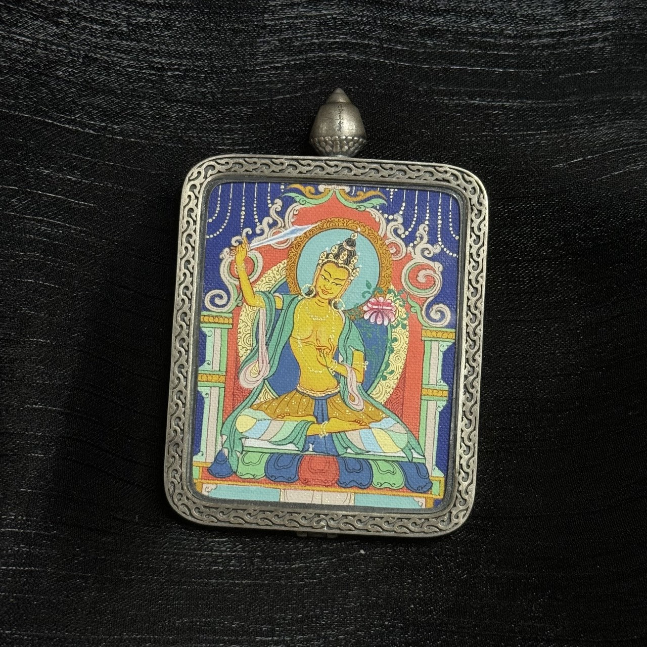 Front view of Manjushri Bodhisattva mini thangka pendant showing detailed mineral pigment painting and engraved silver gawu protective case