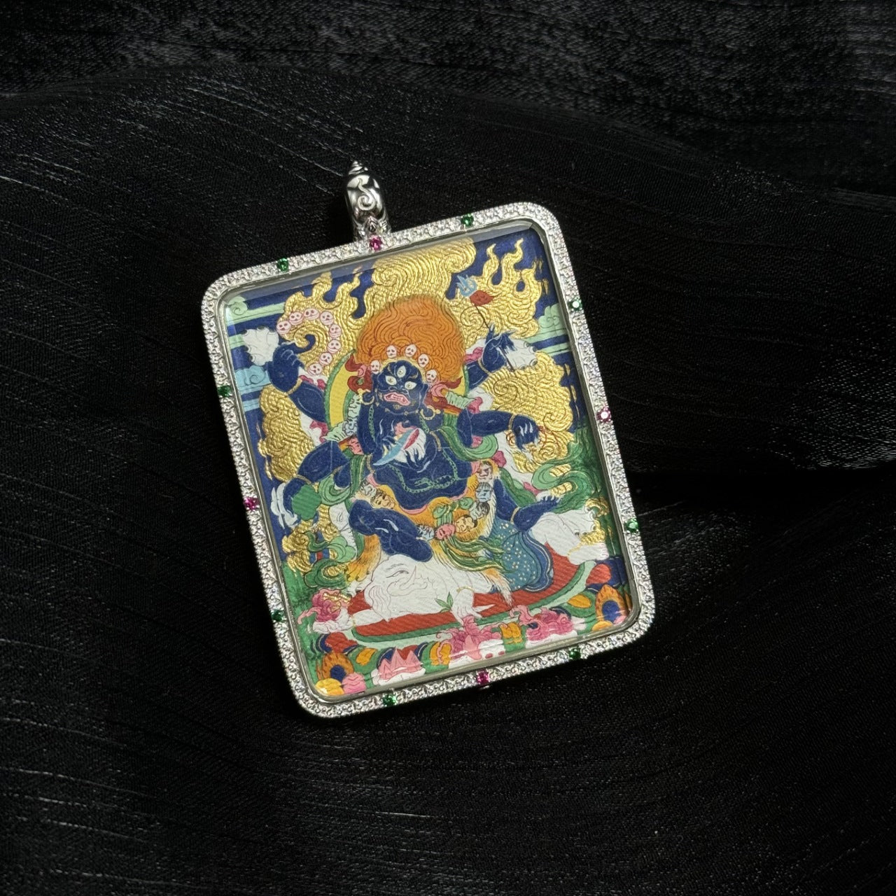 Angled view of Six-Armed Mahakala mini thangka pendant highlighting detailed mineral pigment painting and decorative silver frame with colored stones