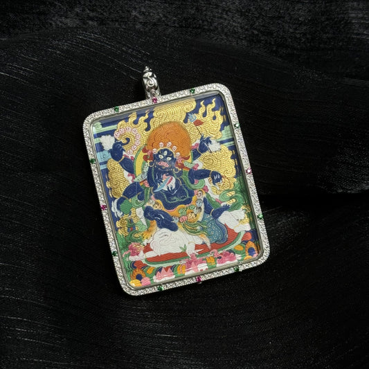 Angled view of Six-Armed Mahakala mini thangka pendant highlighting detailed mineral pigment painting and decorative silver frame with colored stones