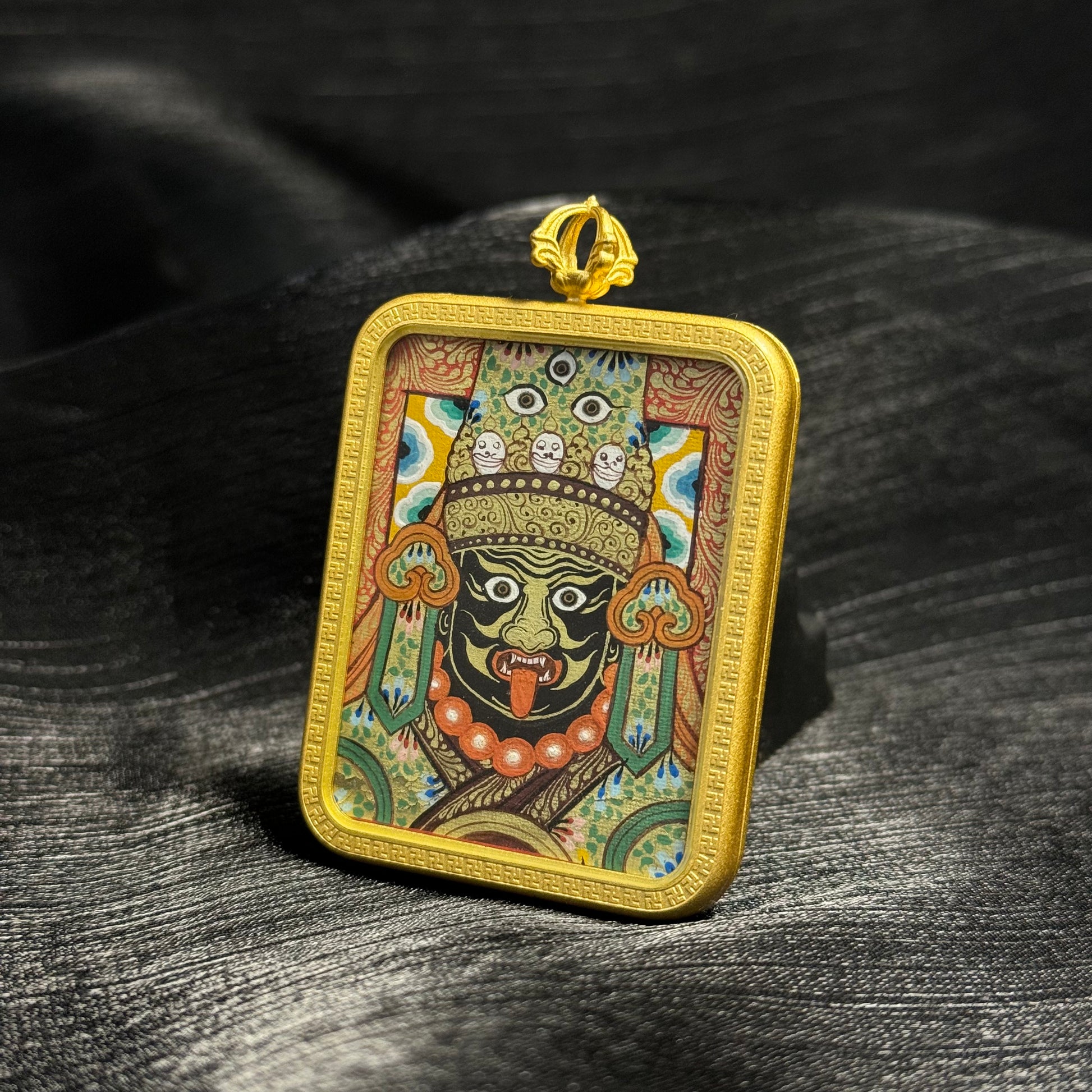 Close perspective of Zaki Lhamo mini thangka pendant highlighting intricate facial features, layered mineral pigments, and gold powder accents typical of Rebgong thangka painting.