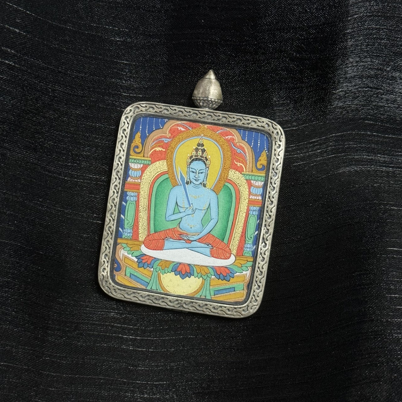 Angled view of Akashagarbha Bodhisattva mini thangka pendant with mineral pigments and engraved silver frame